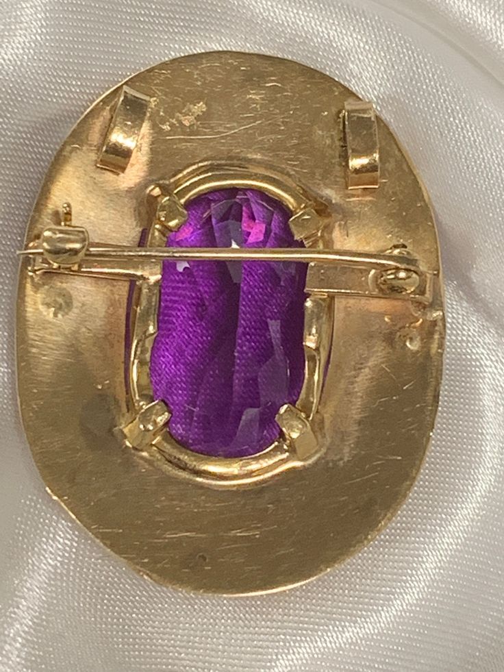 This gorgeous oval 36ctw amethyst is set in a 14kt yellow gold handmade engraved frame adorned with 8 cultured pearls that each measure 2.5mm. It can be worn as a brooch (pin) or a pendant. The amethyst measures 27mmx20mmx12mm, and the entire piece is 38mmx30mm and weighs 10dwt. Handmade in the 1960's it is a true vintage statement piece. It is truly a timeless work of art. Oval Yellow Gold Brooches With Gemstone, Heirloom Oval Gemstone Brooches, Elegant Oval Gemstone Brooches, Luxury Hallmarked Oval Brooch, Antique Oval Gemstone Brooch, Antique Oval Gemstone Brooches, Oval Cabochon Brooches For Anniversary, Heirloom Oval Brooch For Formal Occasions, Oval Brooch In Fine Jewelry Style For Formal Occasions