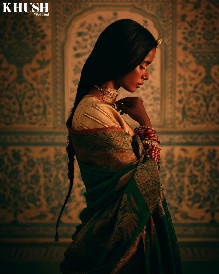 a woman in a green and gold sari with her hands on her hips, looking off to the side