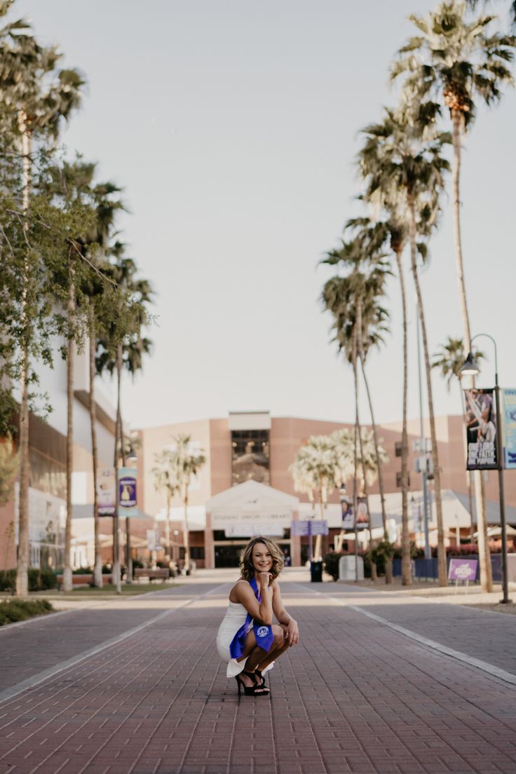 a woman kneeling down on top of a skateboard in the middle of a street