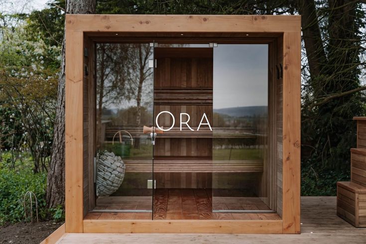 a wooden sauna with the word ora written on it in front of some trees