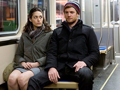 a man and woman sitting on a bench in front of a window with their arms crossed