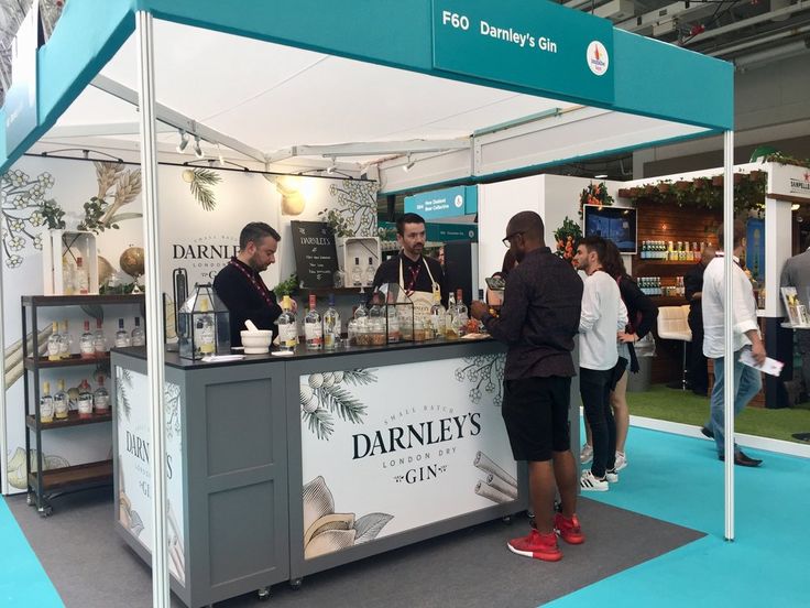 people are standing around at an outdoor stand with drinks on the counter and in front of them