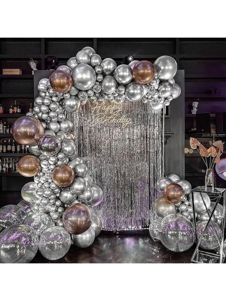 a large balloon arch with silver and gold balloons hanging from it's centerpiece