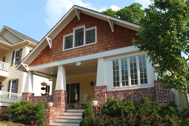 a house with white trim and brown shingles on the front, stairs leading up to it