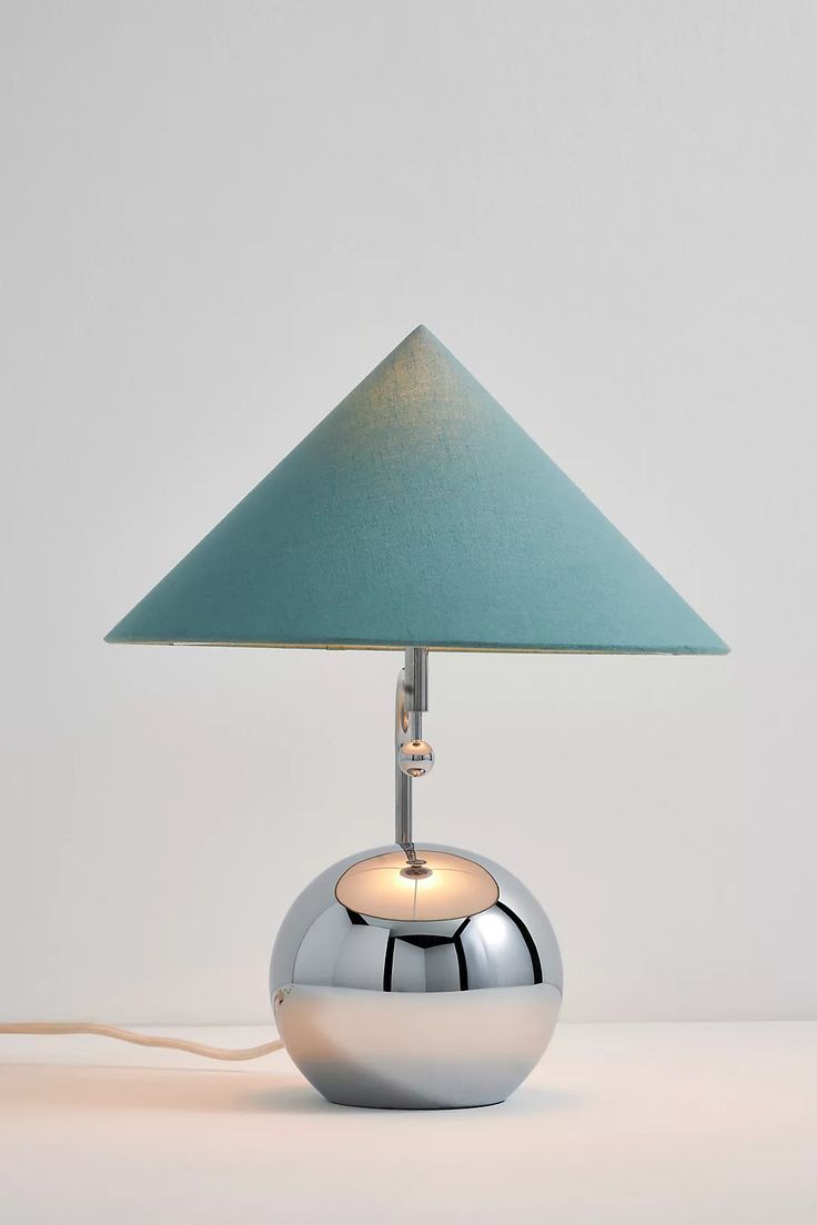 a chrome ball lamp with a blue shade on it's side and a white base