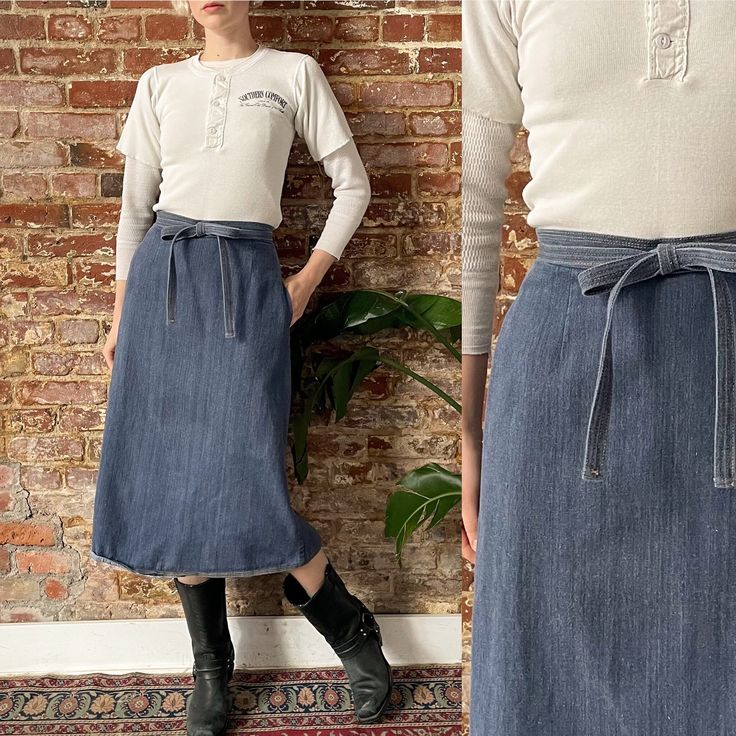 a woman standing in front of a brick wall wearing a denim skirt and white shirt