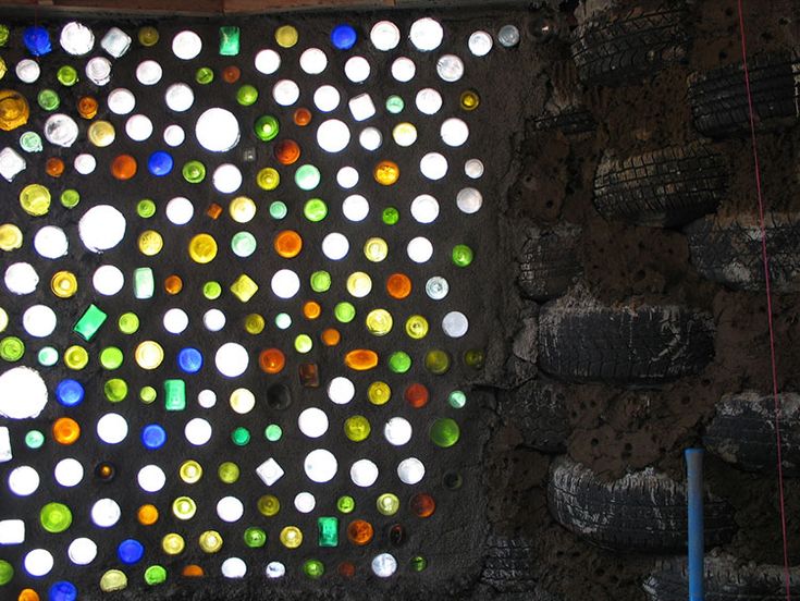 a wall with many different colored glass bottles on it