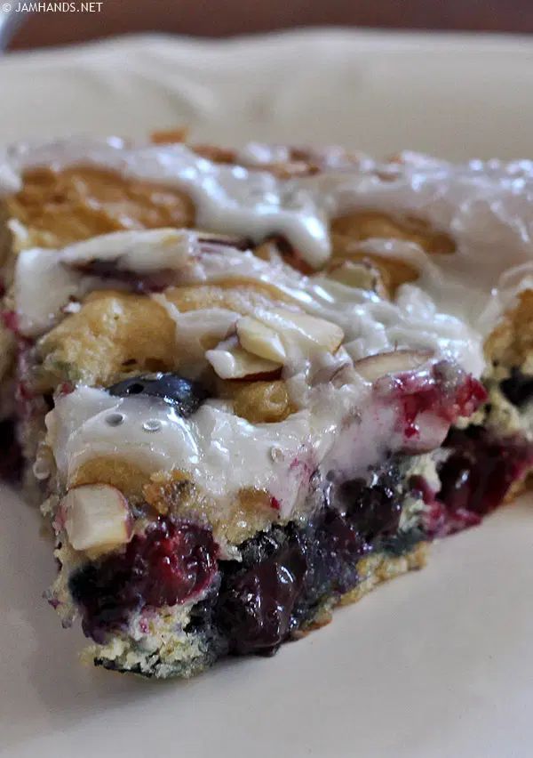 a close up of a piece of cake on a plate with icing and nuts