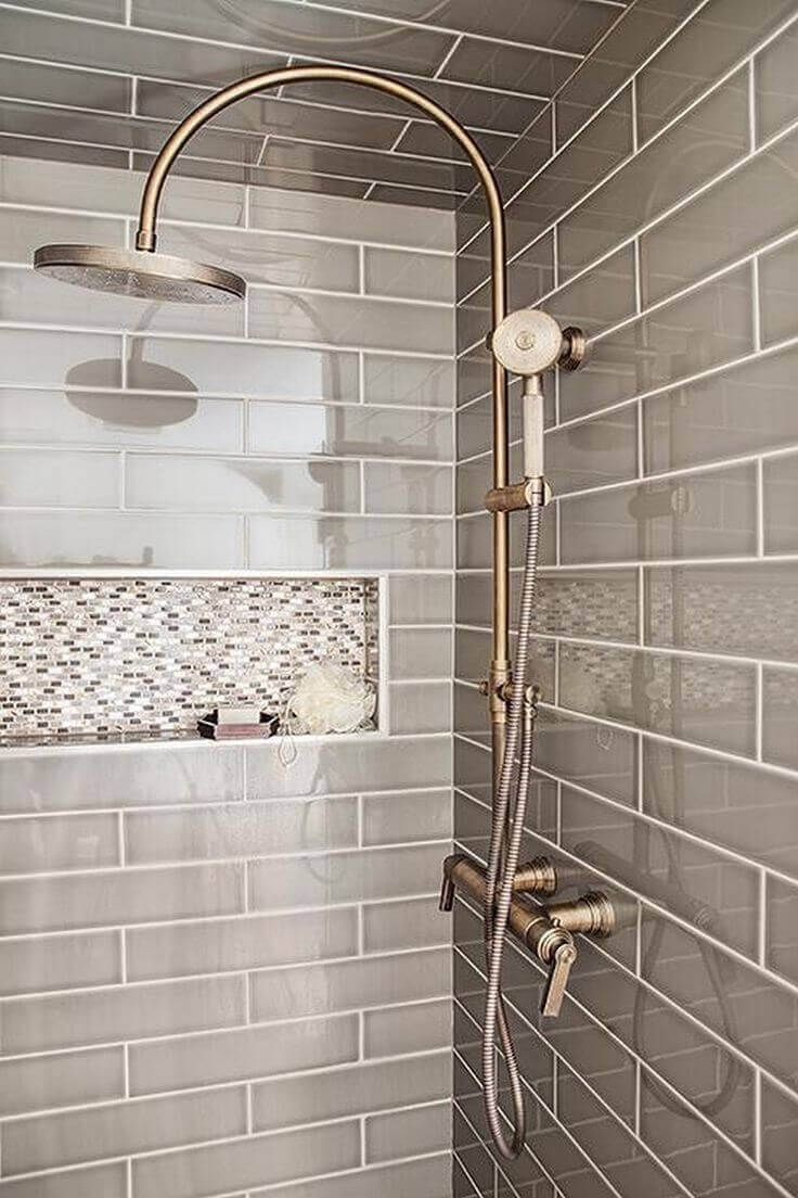 a shower head and hand shower in a bathroom with grey tiles on the wall behind it