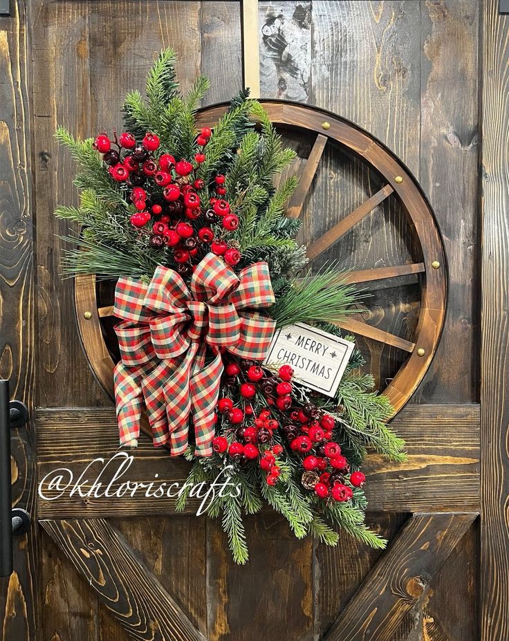 a christmas wreath with red berries and evergreens on a wagon wheel door hanger