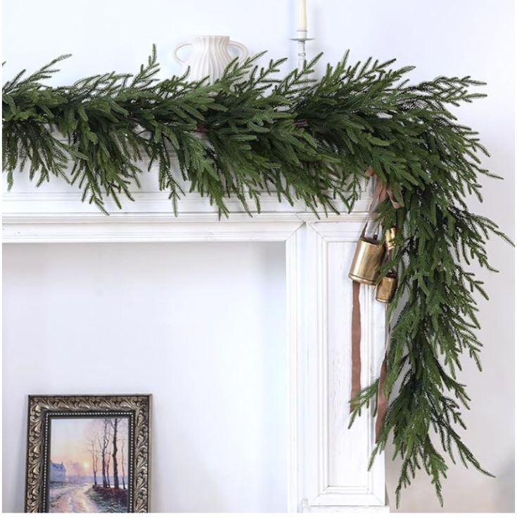 a christmas mantle decorated with greenery and bells