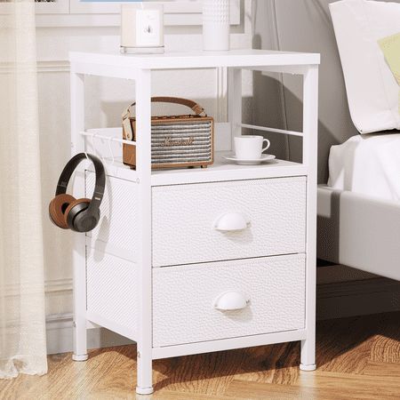 a white night stand with two drawers and a basket on the bottom shelf next to a bed