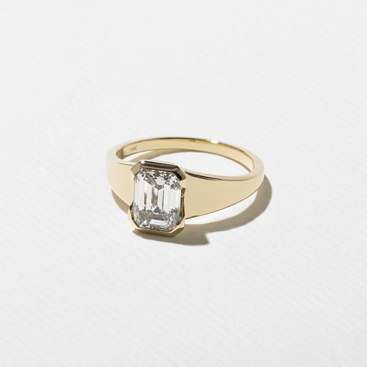 a gold ring with an emerald cut diamond