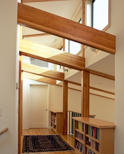 an empty room with wooden floors and bookshelves on the wall, in front of a staircase