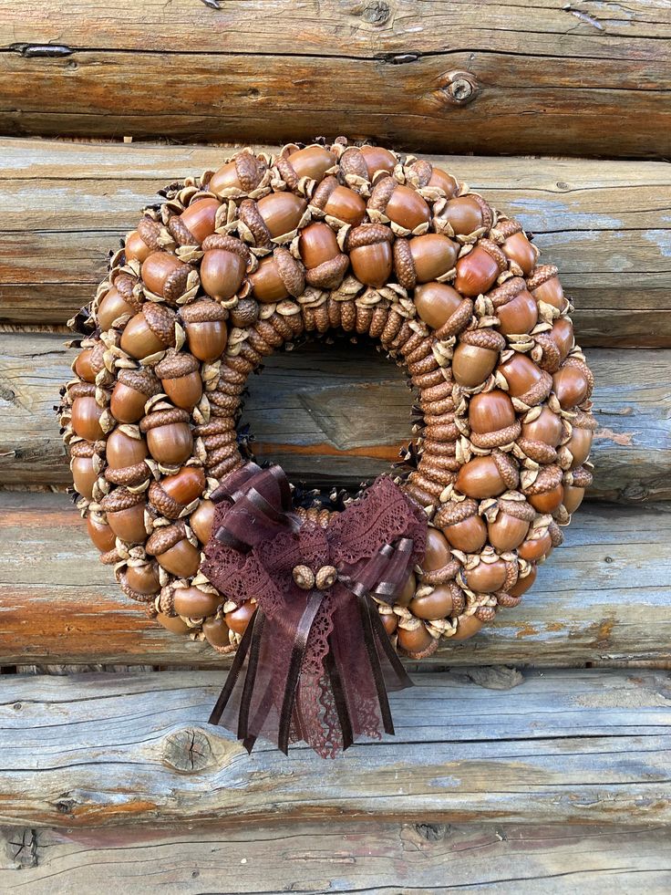 a wreath made out of acorns on a log wall with a brown bow