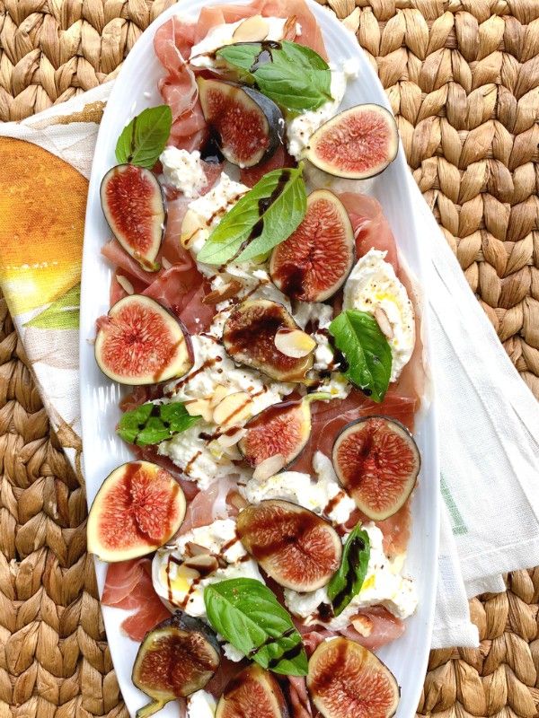 figs and cheese on a platter next to a glass of orange juice