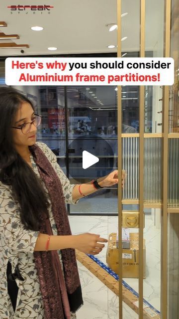 a woman standing in front of a glass display case holding an item with the words here's why you should consider aluminum frame partition