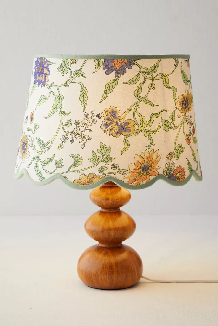 a lamp that is sitting on top of a wooden base with a flower print shade