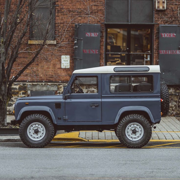 a blue jeep parked in front of a brick building on the side of the road