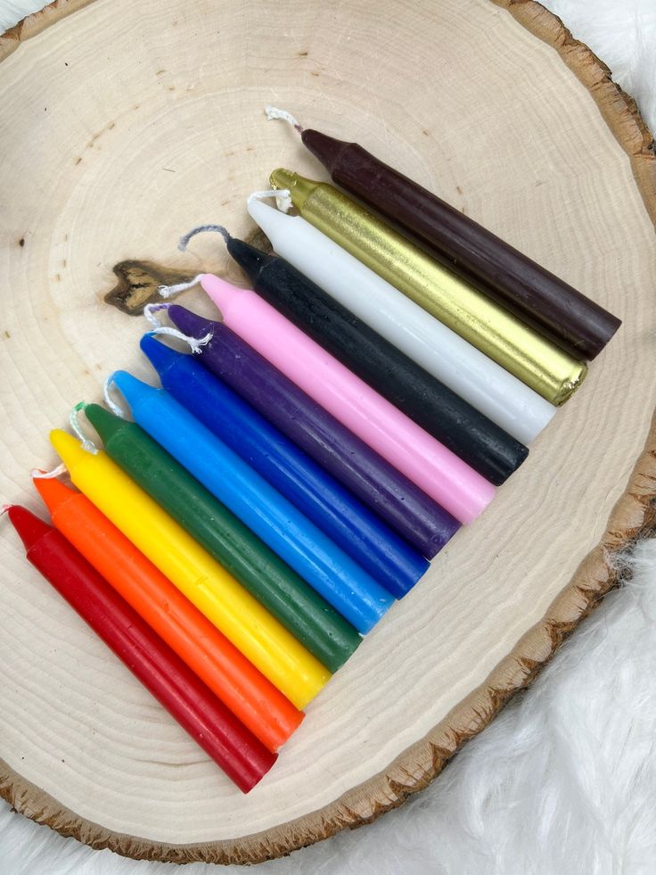 several different colored candles sitting on top of a wooden slice