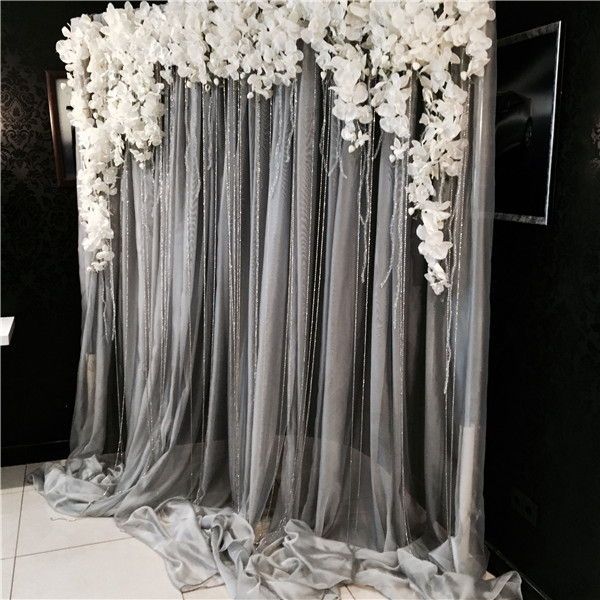 the curtains are covered with white flowers in front of a black wall and tiled floor