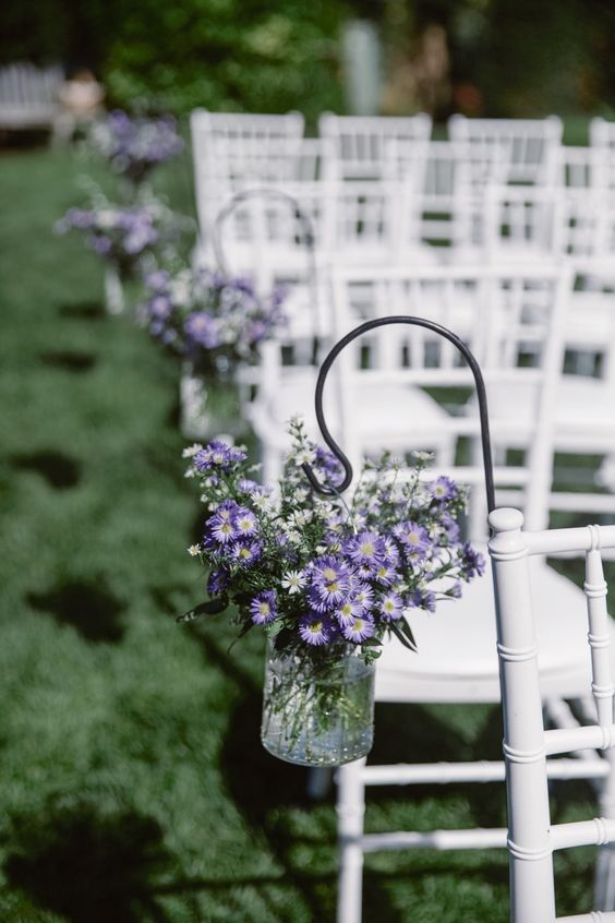 rows of white chairs with purple flowers in them