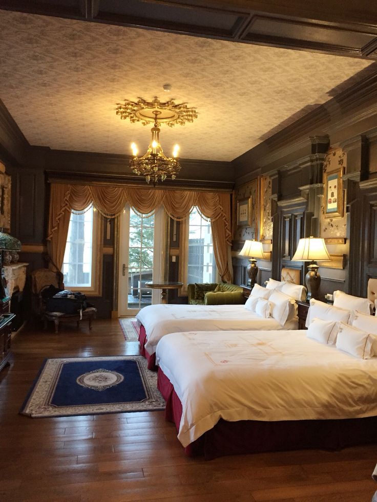 two beds in a large room with chandeliers