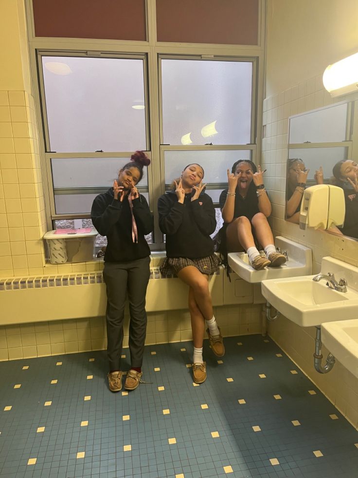 two women are taking pictures in the bathroom