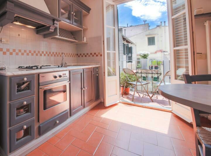 a kitchen with an open door leading to a patio area and outdoor dining table in the background