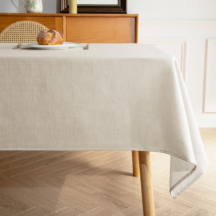 a table with a white cloth on it and a bowl of bread sitting on top of it