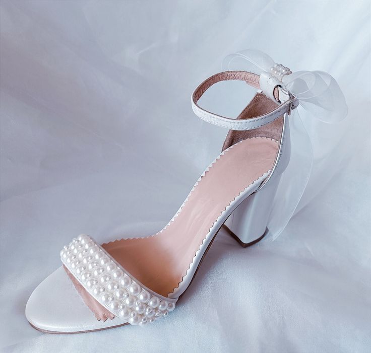 Introducing our exquisite and comfortable wedding sandals, meticulously crafted with the elegant bride in mind. Handmade with utmost care and attention to detail, these wedding pearl heels are the epitome of grace and sophistication. Our Wedding Shoes are designed to capture the essence of romance and enchantment. The delicate organza bow, adds a touch of ethereal charm to these ivory pearl block heels. These comfort shoes are specifically created to ensure that you can dance the night away with ease and grace on your special day. The block heel provides stability and support, allowing you to confidently navigate any terrain. The soft leather lining adds a luxurious feel, pampering your feet with each step you take. Key Features: *Made to order *Elegant and timeless design *Handcrafted wit Closed Toe Wedding Shoes For Summer Guests, Summer Wedding Guest Shoes With Closed Toe, White Pearl Embellished Wedding Shoes For Bridesmaids, Summer Wedding Guest Closed Toe Shoes, Elegant Pearl Embellished Block Heels, Wedding Sandals With 4-inch Heel And Round Toe, Pearl Embellished Low Heels For Summer, Summer Wedding Sandals With 4-inch Heel, Open Heel Wedding Shoes With 4-inch Heel For Guests