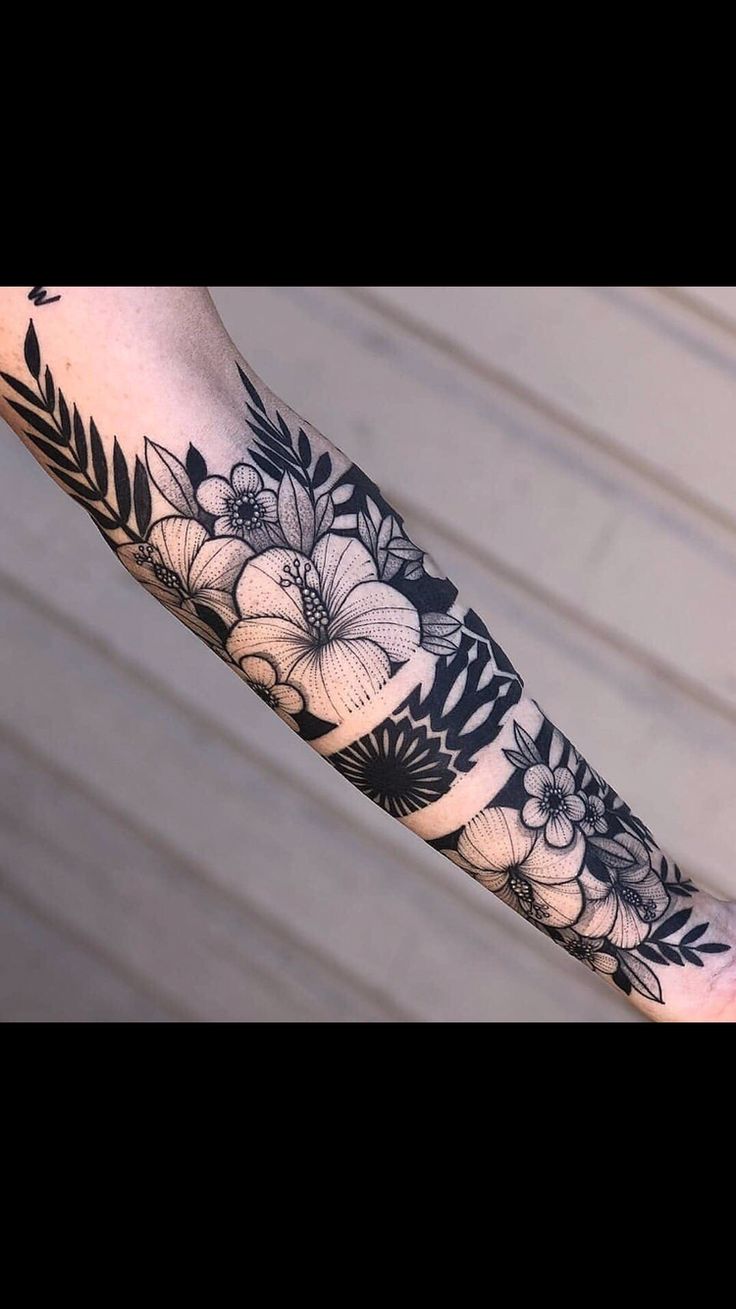 a woman's arm with black and white flowers on the inside of her forearm