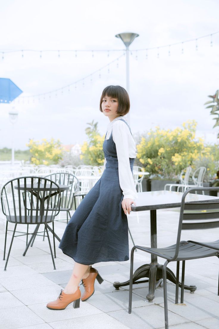 a woman standing next to a table with chairs