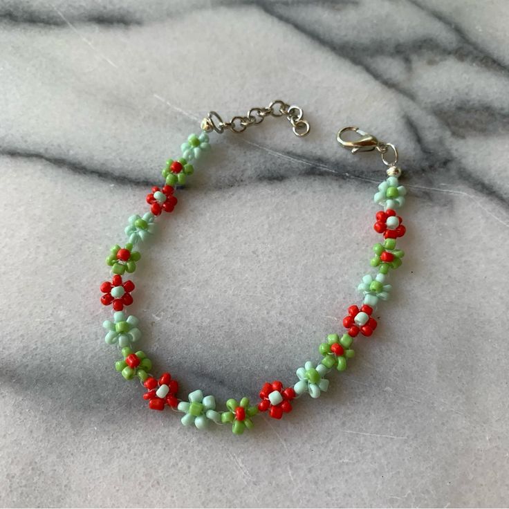 a beaded bracelet with red, green and white beads on a marble table top