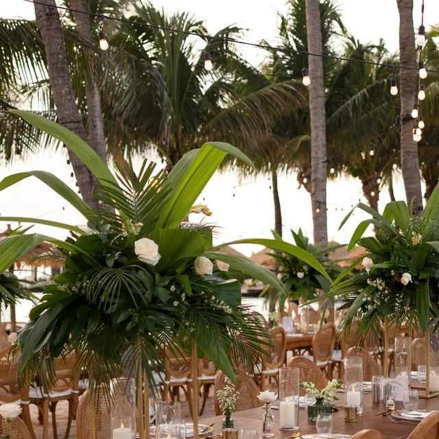 an outdoor dining area with tables, chairs and flowers in vases on the table