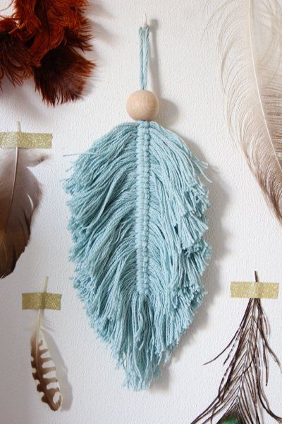 several feathers are hanging on the wall next to a wooden bead ornament