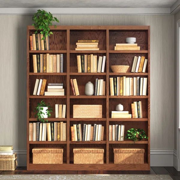 a bookshelf filled with lots of books next to a plant in a room