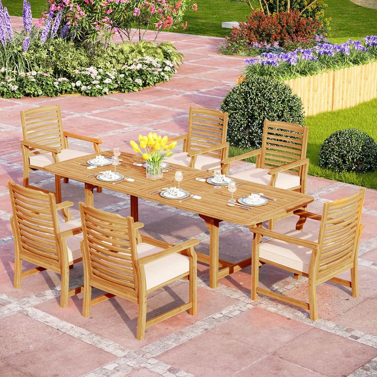 an outdoor dining table and chairs with flowers on the side walk in front of it