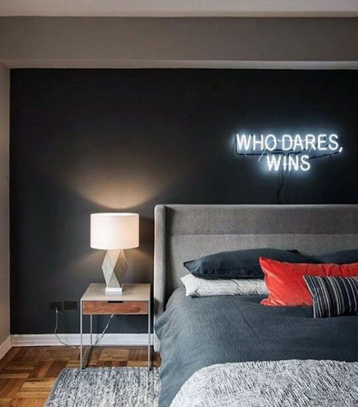 a bedroom with a bed, night stand and neon sign on the wall that says who dares wins