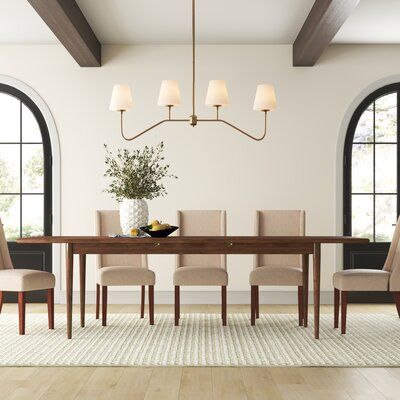 a dining room table with six chairs and a vase on the table in front of it