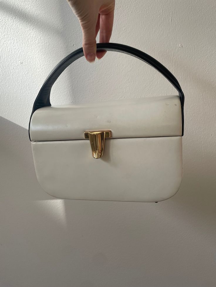 Classically beautiful 1960s bag from Rosenfeld for Saks Fifth Avenue. Light ivory leather with navy sides and handle - great sculptural design. Gold tone clasp. Four protector feet on bottom. Interior is navy grosgrain moire; tag says Rosenfeld Saks Fifth Avenue. From a private collection and stored for many years, this is in very good vintage condition and super usable.  Approx. 8-1/2 wide x 5-1/2 tall (to top of bag) x 4-1/2 front to back. Roomy enough for all your essentials In great vintage Basic Instinct, Mid Modern, Leather Paint, Light Ivory, Top Handle Bags, Handbag Heaven, Vintage Purses, Style And Grace, Vintage Handbags