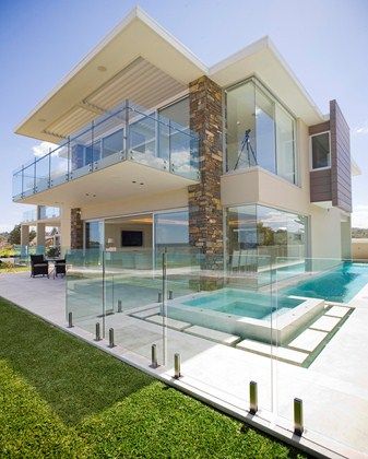 a large house with a pool in front of it and glass balconies on the side