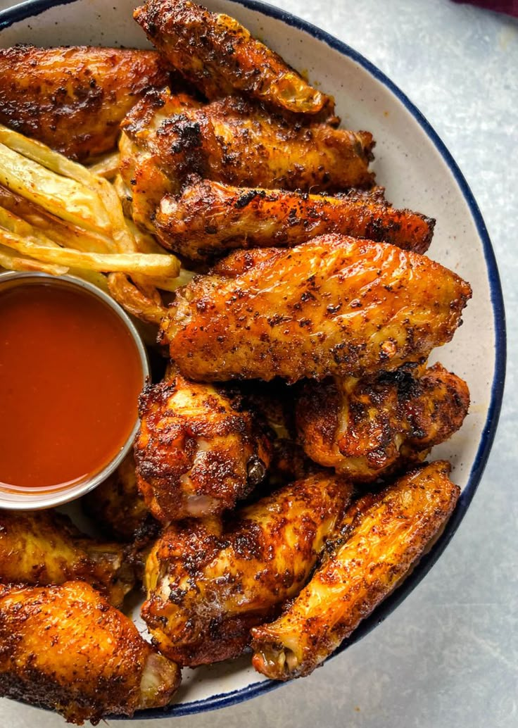 a white plate topped with chicken wings and fries