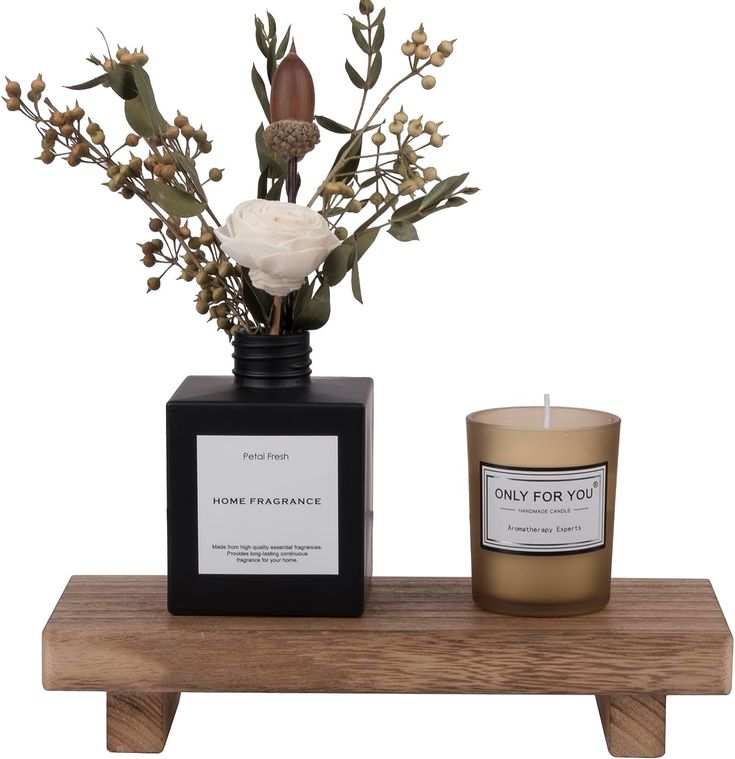 a candle and some flowers on a wooden shelf next to a vase filled with flowers