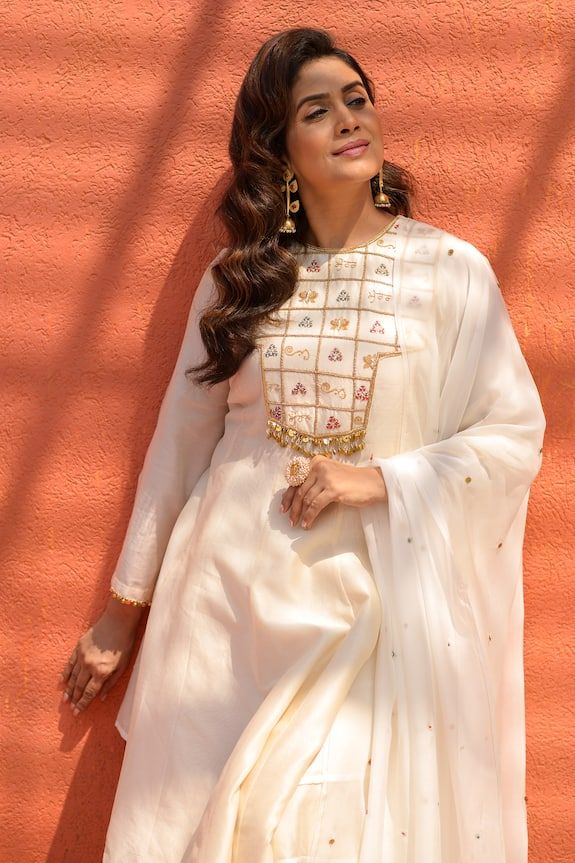 Ivory full flared sleeves asymmetric hem anarkali with sequin bloom, ghungroo embellishments. Paired with a palazzo and sequin embellished dupatta.
Components: 3
Pattern: Embroidery
Type Of Work: Zari, Dori, Sequins, Ghungroo  
Neckline: Round
Sleeve Type: Full Flared Sleeves
Fabric: Chanderi, Organza, Lining: Mulmul Cotton
Color: Ivory
Other Details: 
Note: The hair accessory worn by the model is not for sale
Occasion: Sangeet, Mehendi and Haldi - Aza Fashions Festive Off White Chanderi Palazzo Set, White Dress For Diwali Celebration, Off White Sharara With Dabka Work In Traditional Drape, Off White Dabka Work Sharara With Traditional Drape, Off White Sharara With Zari Work And Straight Kurta, Cream Kurta With Gota Work In Traditional Style, White Chinon Palazzo Set With Dupatta, White Chinon Palazzo Set With Straight Kurta, Festive Designer Off White Palazzo Set