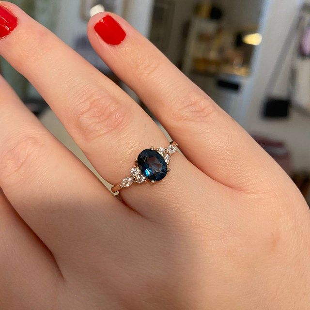 a woman's hand with a ring on it and a blue stone in the middle