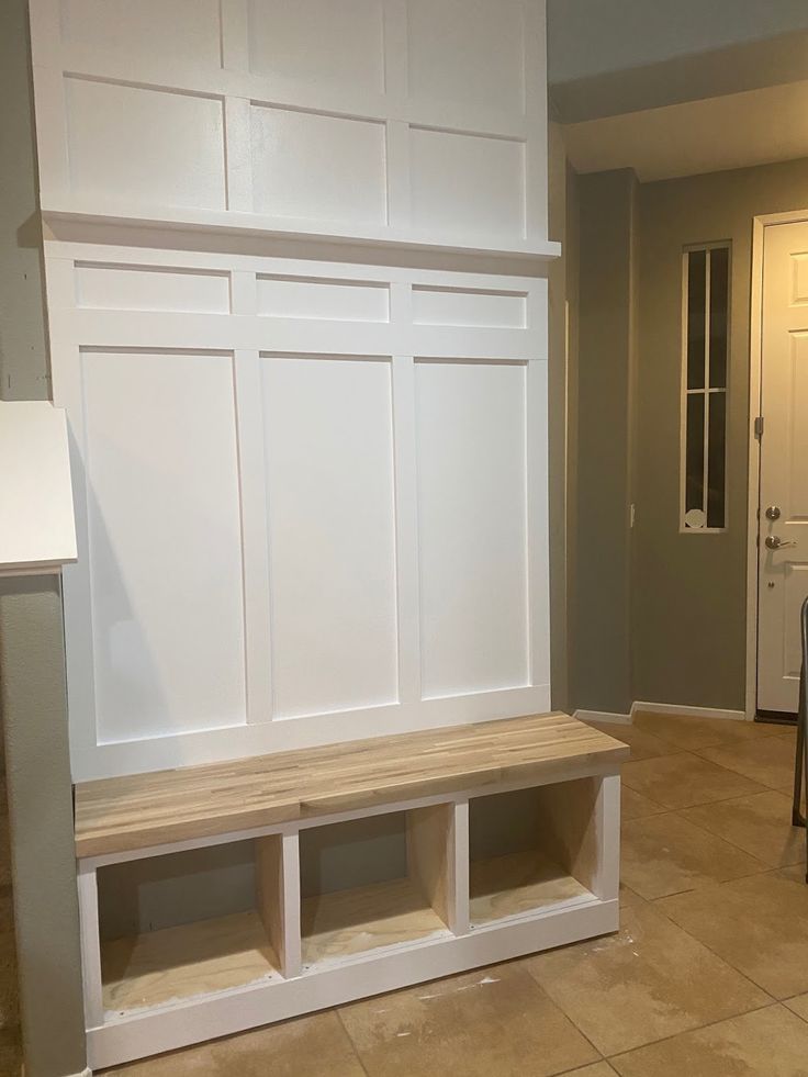 a kitchen with white cabinets and wooden bench in the center, next to an open door