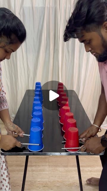 two people standing over a table with cups on it