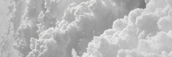 black and white photograph of clouds in the sky with jetliners flying above them