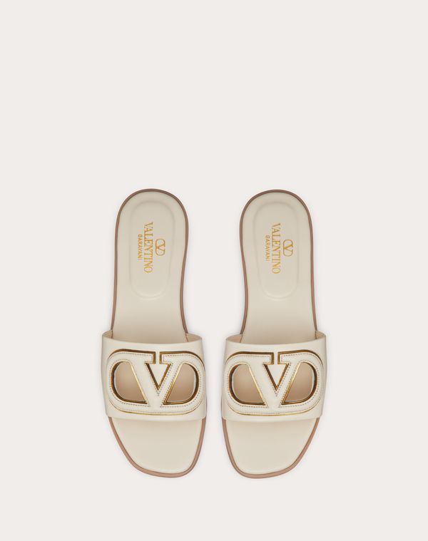 Valentino Garavani VLogo cut-out slide sandal in calfskin leather - VLogo Signature cut-out calfskin detail with mirror-effect trim - Insole with padded heel for extra comfort - Heel height: 5 mm / 0.2 in. - Made in Italy White Luxury Calf Leather Mules, Luxury White Calf Leather Mules, White Calf Leather Mules, Luxury Cream Mules, Elegant Flat Calf Leather Slides, Calf Leather Open Toe Slides, Luxury Calf Leather Open Heel Slides, Calf Leather Slides With Branded Insole And Open Heel, Luxury Mules With Leather Footbed And Open Heel